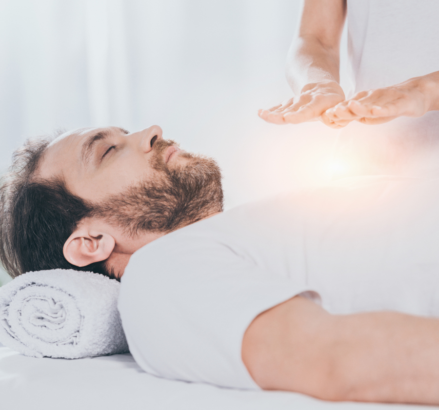 cropped shot of bearded man with closed eyes receiving reiki treatment on chest